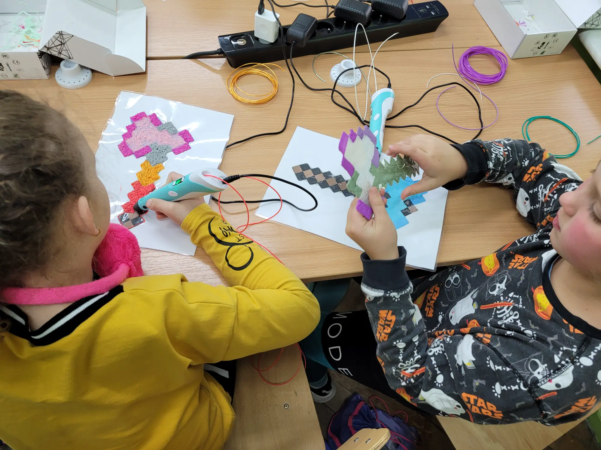 Dzieci tworzą kolorowe prace długopisami 3D na szablonach