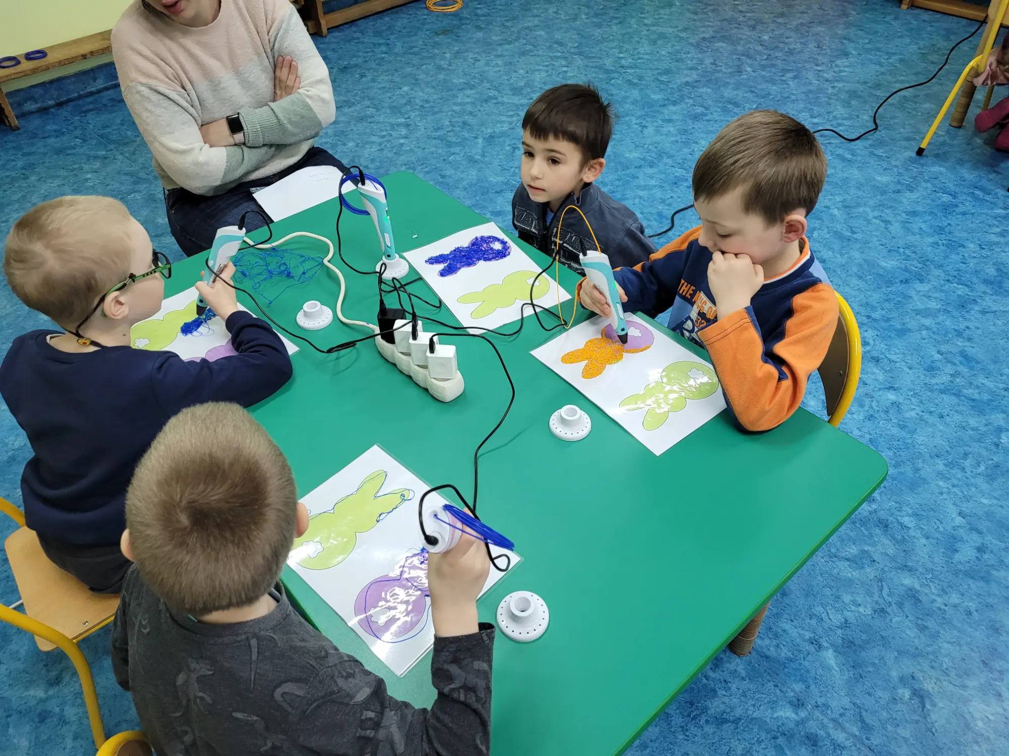 Dzieci pracują z długopisami 3D przy stole w przedszkolu