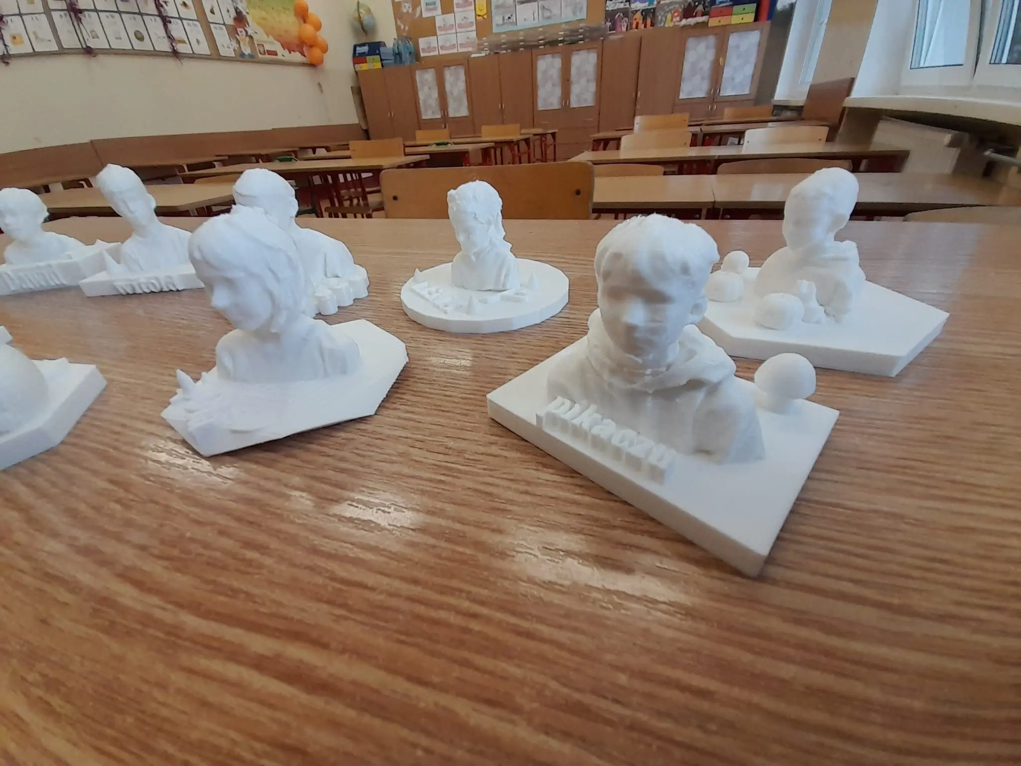 Białe wydruki 3D popiersi na szkolnej ławce
