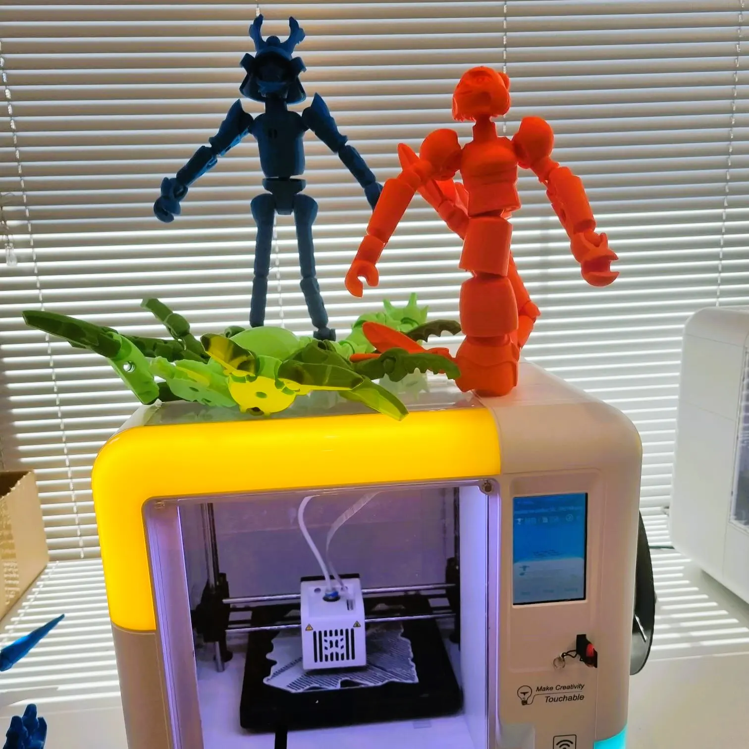 Wydrukowane figurki ustawione na obudowie drukarki 3D