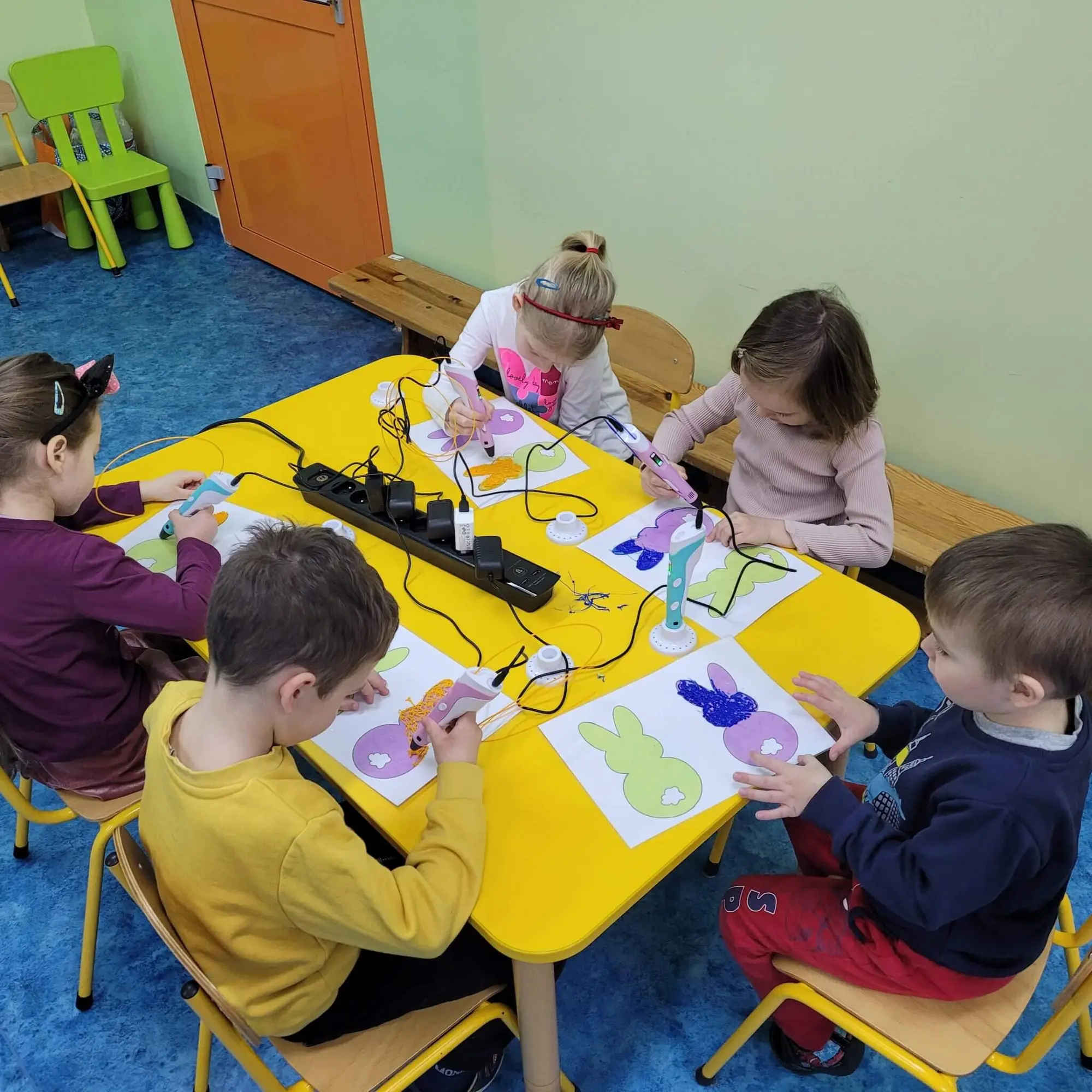 Przedszkolaki przy stolikach podczas zajęć z długopisami 3D